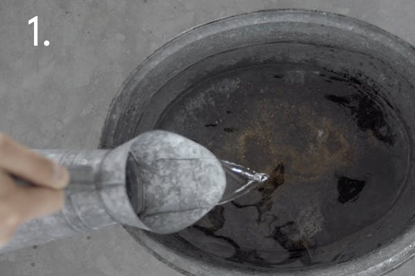 steg 1 dress Vatten hälls från en kanna ner i en metall balja i ett handskmakeri