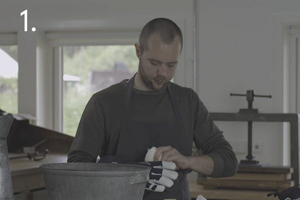 steg 1 sport En handskmakare använder en fuktig trasa på ett par skidhandskar i ett handskmakeri