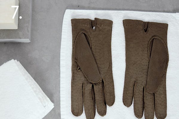 steg 7 dress Ett par bruna skinnhandskar ligger på en vit handduk för att torka i ett handskmakeri