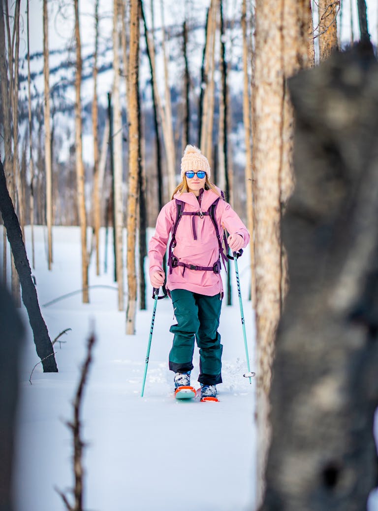 MPOON_20200228_02760 (kopia) En kvinna i rosa jacka och gröna byxor vandrar på snötäckta stigar bland träden i ett vinterlandskap