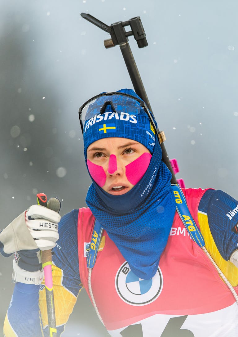 Biathlon, IBU World Cup, day 6, Women's 7,5 km sprint En kvinna i tävlingsdräkt och längdskidhandskar förbereder sig för tävling i snöiga förhållanden