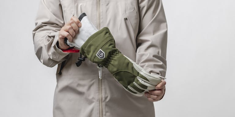_D5A5409 (3) Person in beige shell jacket holding a green ski glove with a removable inner glove