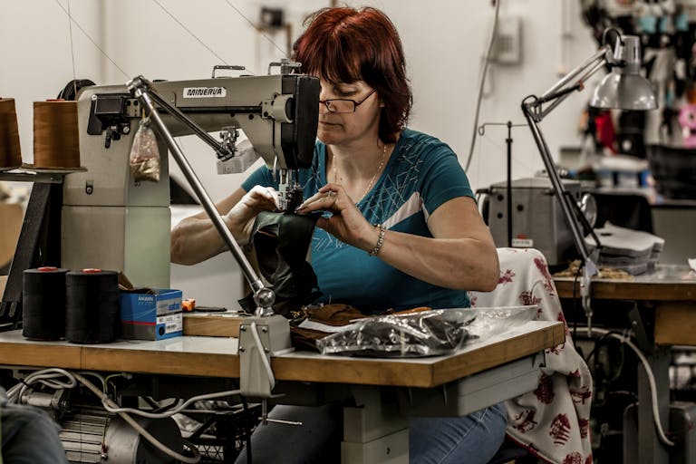 _MG_3712 A seamstress is sewing gloves with a sewing machine in a factory environment
