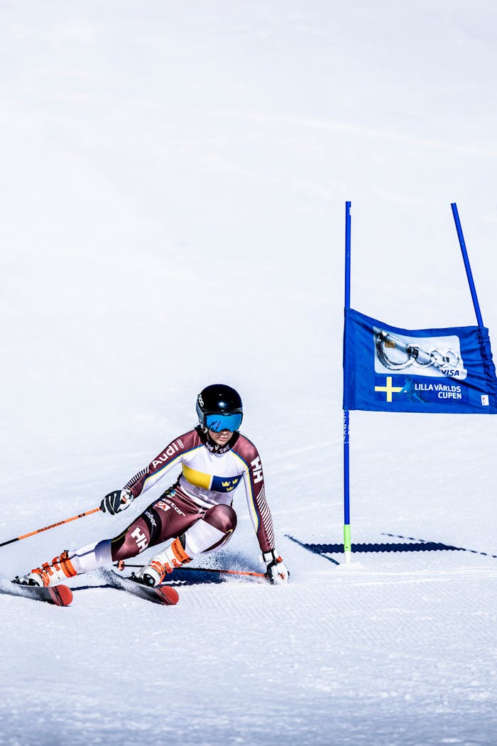An alpine skier races slalom at high speed between gates on a sunny snow-covered slope in the mountains