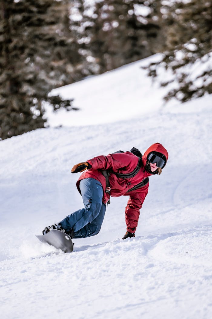 Snowboarder fährt mit reflektierender Schutzbrille und Winterausrüstung eine Kurve