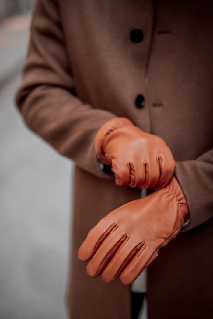 Ein Mann trägt an einem kalten Tag in der Stadt braune Lederhandschuhe und einen dunklen Mantel