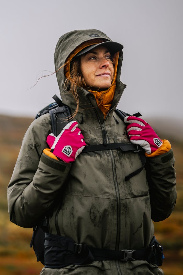 Eine Person steht entspannt in Outdoor-Kleidung in der Natur und blickt in den Himmel